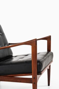 a black leather chair sitting on top of a white floor next to a wooden frame