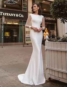 a woman standing in front of a building wearing a white dress