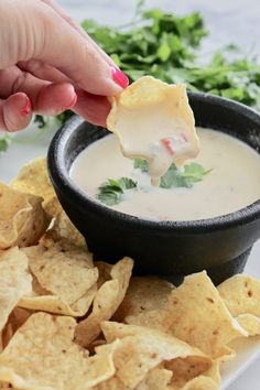 a person dipping tortilla chips into a bowl of dip