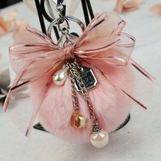 a keychain with a pink bow and pearls on it