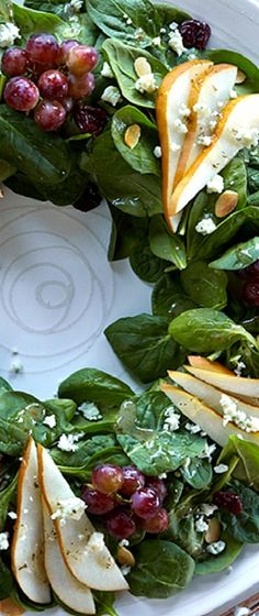 a white plate topped with spinach and apple slices on top of a wreath shaped dish