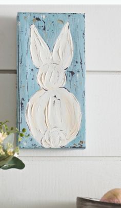 a painting of a white rabbit on a blue background next to some flowers and an apple