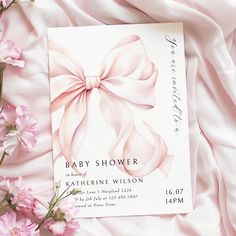 a baby shower card with pink flowers in the foreground and an image of a bow on it