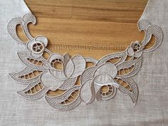 an embroidered collar with flowers and leaves is shown on a piece of linen, next to a wooden box