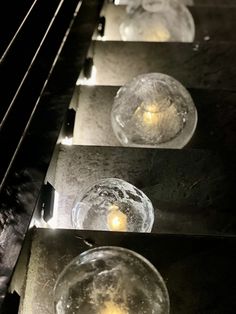 three glass bowls with candles in them sitting on a shelf next to some metal bars