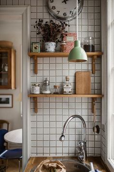 a kitchen sink under a large clock mounted on a wall above it's counter