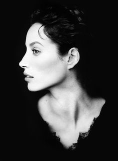 a black and white photo of a woman's face with her hair pulled back