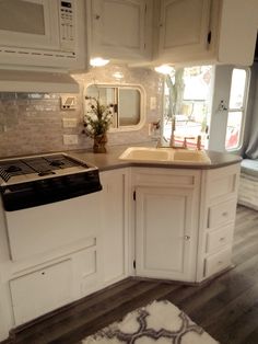 a kitchen with white cabinets and an oven in the center is lit by recessed lights