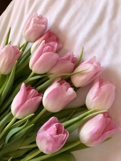 a bunch of pink tulips laying on top of a bed