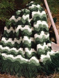 a green and white blanket sitting on top of a wooden wheelbarrow in the grass