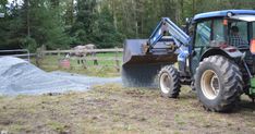 a blue tractor is parked next to a pile of dirt