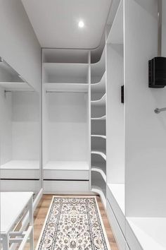 an empty walk in closet with white walls and shelving units on each side, along with a rug