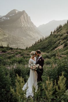 a bride and groom standing in the mountains