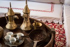 a tray that has some cups and spoons on it in front of a bed