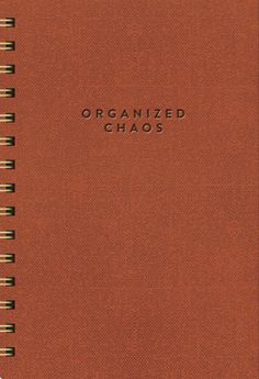 an orange spiral bound notebook with the words organized chaos written in black on top of it