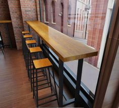 there are many stools at the bar in this restaurant that is very long and narrow