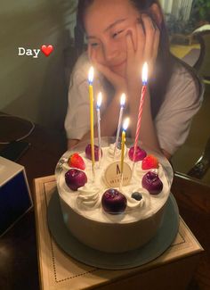 a woman sitting in front of a cake with candles on it and her face behind the cake