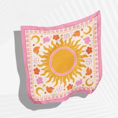 a pink and yellow square scarf with an image of the sun on it, against a white background