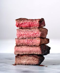 a stack of four steaks sitting on top of a counter next to each other