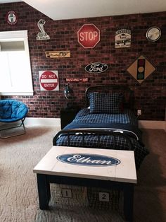 a bedroom with a brick wall and various signs on the walls, including a bed