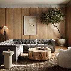 a living room with wood paneled walls and leather couches, coffee table, potted olive tree in the corner