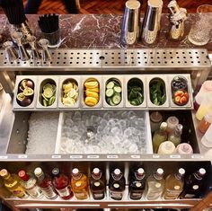 an assortment of drinks and condiments are arranged on a silver bar with marble counter top