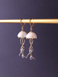 Introducing our stunning Jellyfish Earrings, crafted with utmost care and fashioned with a unique blend of resin, curved metal charms, and delicate teardrop beads. These enchanting earrings capture the graceful movement of jellyfish in a captivating design that is sure to turn heads. Each intricately detailed jellyfish is meticulously molded from resin, showcasing their ethereal beauty. The curved metal charms add a touch of elegance and whimsy, perfectly complemented by the shimmering teardrop White Jelly Fish, Jellyfish Earring, Jellyfish Jewelry, Jellyfish Earrings, Ethereal Jewelry, Graceful Movement, Bracelet Inspo, Art Help, Jelly Fish