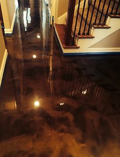 the floor is shiny and dark in this hallway, with stairs leading up to the second floor