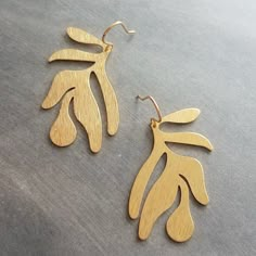 Large tropical leaves of raw brass and given a brushed / lightly striated finish on 14K gold plated brass ear hooks. Extremely lightweight- I'll include a pair of silicone stoppers so you can wear without fear of losing them!  Optional HOOK upgrade to 14K SOLID gold or 14K gold fill - both are a wonderful option for some people with metal allergies.  { A b o u t   R a w   B r a s s } Leaves are raw brass that I have shined up with a jeweler's polishing cloth. They will darken a bit naturally over time / wear and can be quickly polished back to its original shine at any time with any jewelry polishing cloth marked safe for raw / unplated brass (be sure to polish leaf , not the hook, as it is not raw brass). { M e a s u r e m e n t s } Entire length of earring from where inserted into ear is Large Gold Earrings, Tropical Earrings, Leaf Earring, Metal Jewellery, Beach Earrings, Gold Leaf Earrings, Heirlooms Jewelry, Tropical Leaf, Big Earrings