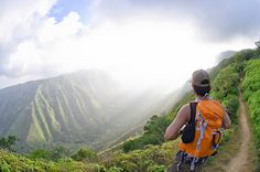 a man hiking up the side of a lush green hillside