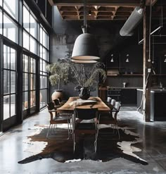 an industrial style dining room with black walls and flooring, wooden table surrounded by cow hide rugs