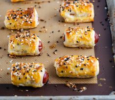 hot dogs with cheese and sesame seeds on a baking sheet