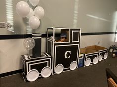 there is a train made out of cardboard boxes with balloons in the back and on top