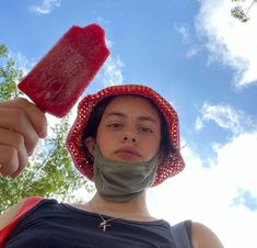 a woman wearing a bandana and holding a popsicle in front of her face