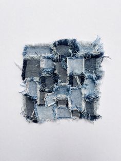 an old piece of denim with holes and frays on the side, sitting in front of a white wall