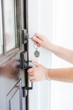 a woman is opening the door with her hand and keychain to open it