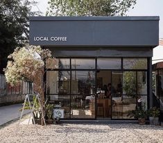 a coffee shop sitting on the side of a road with lots of plants in front of it