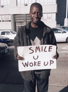 a man holding a sign that says smile u woke up