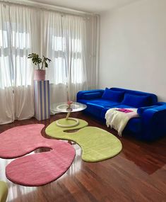 a living room with blue couches and rugs on the wooden floor, near a large window