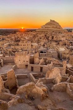 the sun is setting over an ancient city in africa, with adobe buildings and stone structures