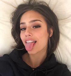 a woman sticking her tongue out while laying in bed