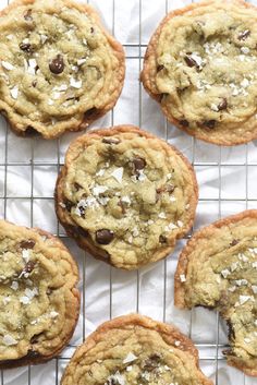 chocolate chip cookies on a cooling rack with coconut flakes all over the top and one cookie in the middle