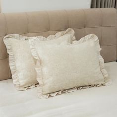 two pillows sitting on top of a bed next to each other in front of a headboard