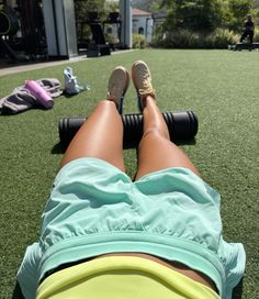 a woman laying on top of a green field next to a pair of legs with shoes on