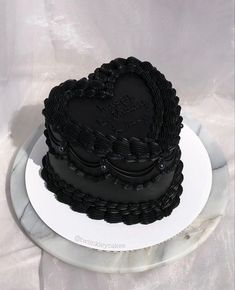 a black heart shaped cake on a white plate