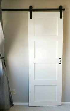 an empty room with a white door and black handles