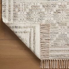 an area rug with fringes on the top and bottom, laying on a wooden floor