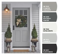 the front door is painted gray and has three potted plants on each planter