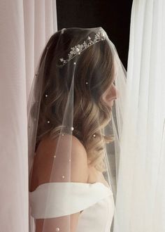 a woman wearing a veil with pearls on it