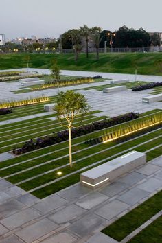 an aerial view of a park with benches and trees in the center, lit up at night